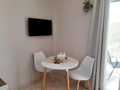 a table and chairs in a room with a tv at Verano Vista Apartment_near the sea-free parking in Analipsi