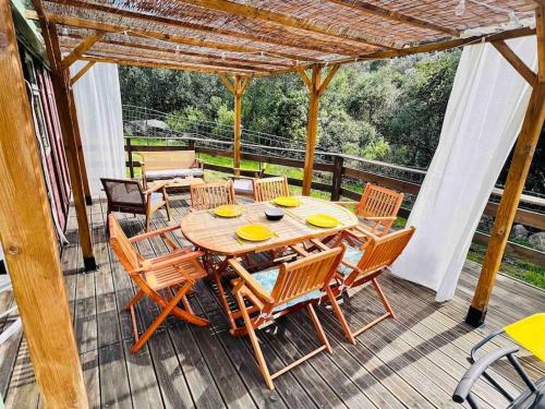une table et des chaises en bois sur une terrasse dans l'établissement Chalet au calme à Sagone en Corse, à Sagone