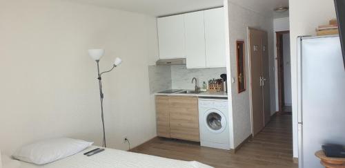 ein Zimmer mit einem Bett und eine Küche mit einer Waschmaschine in der Unterkunft Studio Gruissan Vue Port in Gruissan