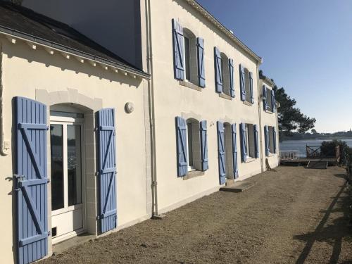 - un bâtiment blanc avec des portes et des fenêtres bleues dans l'établissement Havre de Paix les pieds dans l'eau, à Locoal-Mendon