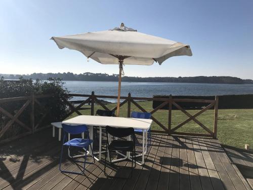 une table et des chaises sous un parasol sur une terrasse dans l'établissement Havre de Paix les pieds dans l'eau, à Locoal-Mendon