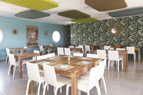 a dining room with wooden tables and white chairs at Location appartement les pieds dans l'eau, Résidence Aqua Linda à Poggio-Mezzana in Poggio-Mezzana