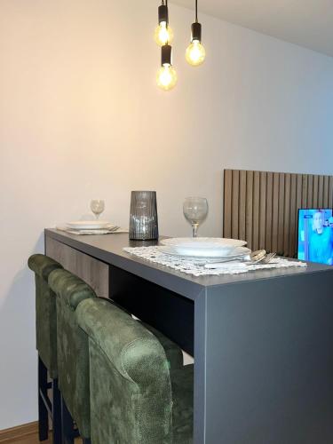 a bar with a green couch under a table with glasses at Apartmani Profesional Pajkovic in Valjevo