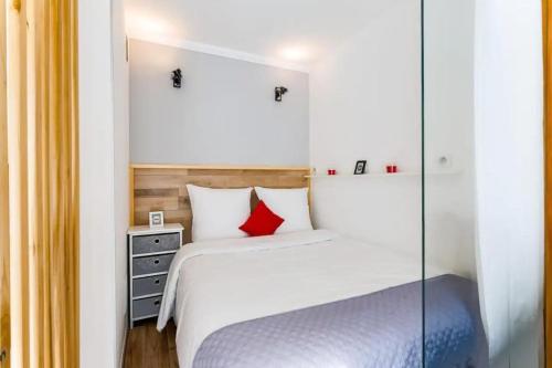 um quarto com uma cama branca e uma almofada vermelha em Studio Central 300 m des plages, au calme em Cannes