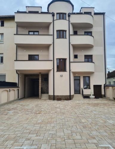 a large white building with a large parking lot at Apartmani Profesional Pajkovic in Valjevo