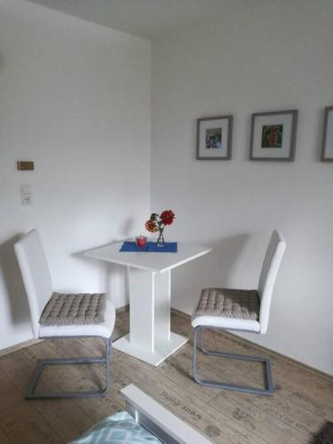 a white table with two chairs and a table with a vase at Appartment, gemütlich u. zentral in Hattingen