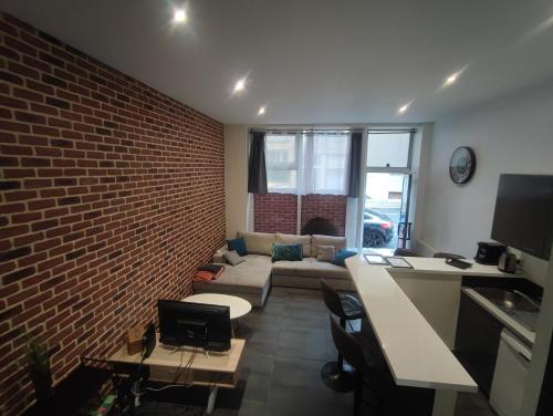 a living room with a couch and a brick wall at Le Havre, 1 chambre , appartement Sympa en centre ville in Le Havre