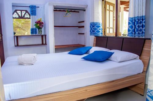 a bedroom with a large white bed with blue pillows at DiNi Galle in Galle