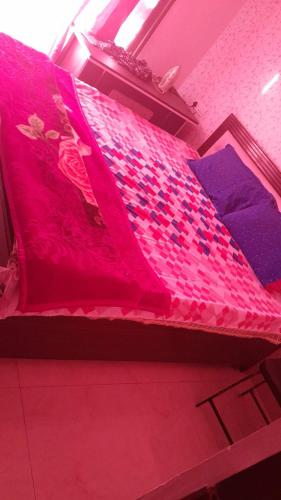 a bed with a pink blanket and purple pillows at Rellio Bed and Breakfast in Kharar