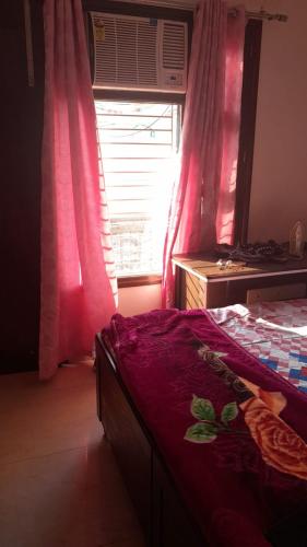 a bedroom with a bed and a window with pink curtains at Rellio Bed and Breakfast in Kharar
