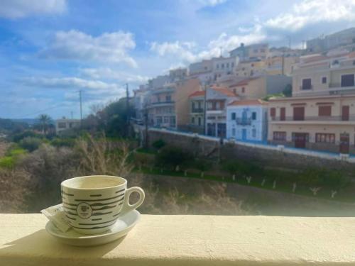 a coffee cup sitting on a ledge with a view of a city at Mesa Vrisi in Karpathos