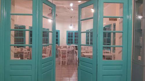 a room with green doors and a dining room with tables at Mesa Vrisi in Karpathos