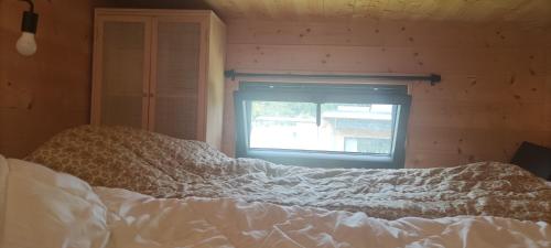 Bett in einem Zimmer mit Fenster in der Unterkunft Tiny house bucolique in Saint-Brieuc-de-Mauron