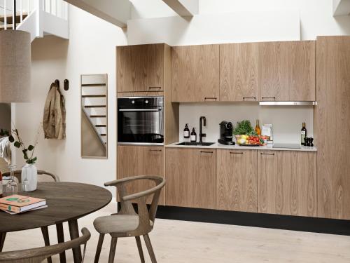 a kitchen with wooden cabinets and a table at Aura Apartment Hotel in Aarhus