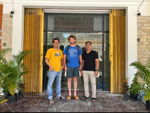 a group of three men standing in front of a door at White House Guesthouse in Phnom Penh