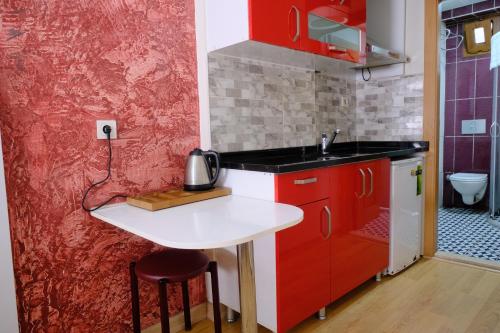 una pequeña cocina con armarios rojos y fregadero en Taksim Green Suites, en Estambul