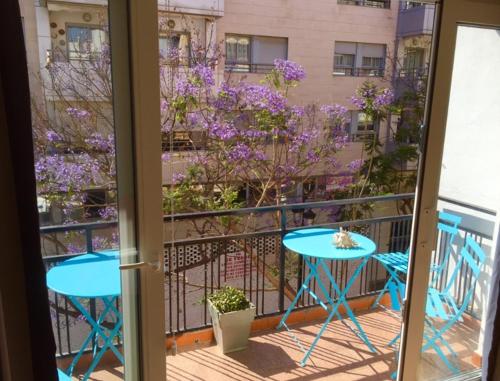 einen Balkon mit einem Tisch, Stühlen und lila Blumen in der Unterkunft Ramon - Y - Cajal in Fuengirola