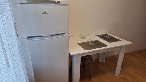 a white refrigerator next to a white table with a small table at У Тахира in Almaty