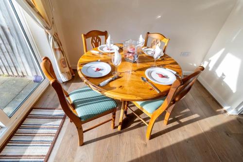 einem Holztisch mit Stühlen, einem Holztisch und einem Tisch in der Unterkunft Cosy 3 bedroom house in Stoke on Trent