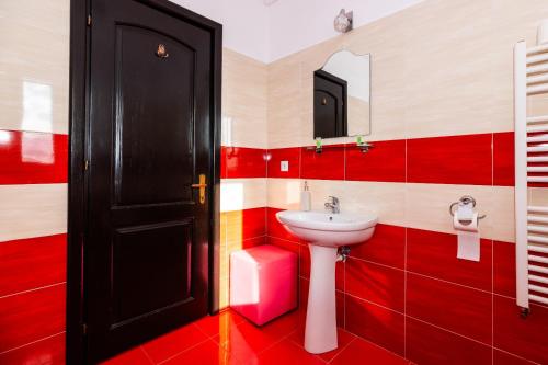 a red and white bathroom with a sink and a mirror at VILA LUCA-Hotel in Şirnea