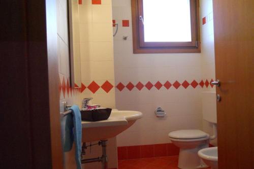 ein Bad mit einem Waschbecken und einem WC in der Unterkunft Lovely holiday home with fenced garden and pool in Bibione