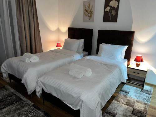 two beds in a bedroom with white sheets and towels at Apartmani Profesional Pajkovic in Valjevo