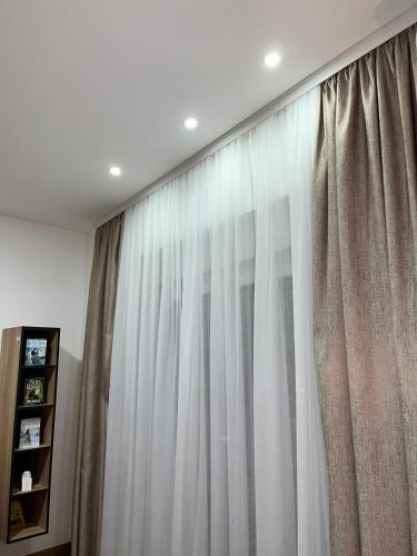 a window with white curtains in a room at Apartmani Profesional Pajkovic in Valjevo