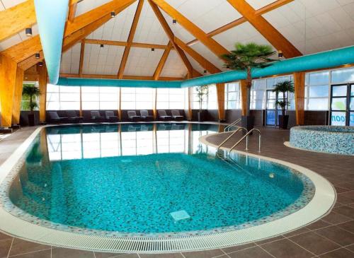 una gran piscina de agua azul en un edificio en Family friendly holiday home en Hulshorst