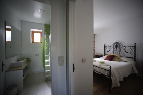 a bedroom with a bed and a door leading to a bathroom at Apartamentos Rurais - Casas do Lagar in Rosmaninhal