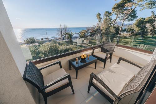 a balcony with chairs and a table and the ocean at Apartments Kuce Lekovica Beach & snack bar- Bistro in Bar