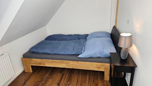 a bed with blue pillows and a table and a lamp at Ferienwohnungen An den SchwabachAuen - Keine Monteure in Eckental