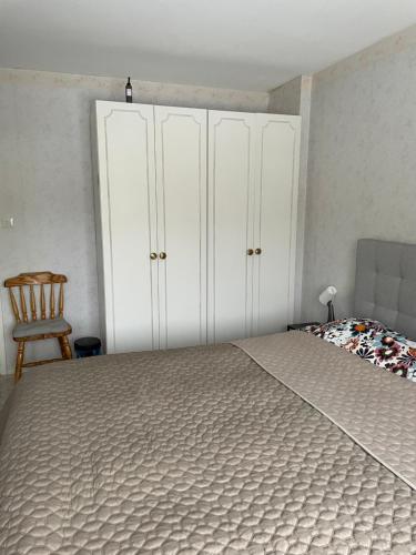 a bedroom with a bed with white cabinets and a chair at Cozy Rooms between Airport&Center in Stockholm