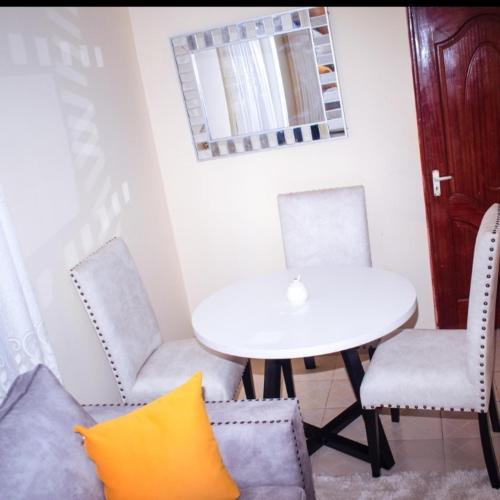une table et des chaises avec une table blanche et un oreiller jaune dans l'établissement muindi homes, à Kitui