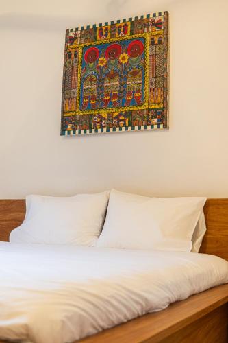 a bed with white sheets and a painting on the wall at Oxygen Paje Hotel in Paje