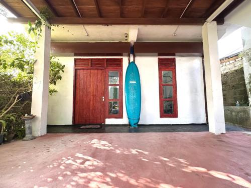 una tabla de surf azul sentada en un lado de una casa en Sana Studio, en Weligama