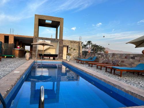 a swimming pool with benches and umbrellas next to a building at Nile Panorama Hotel in Luxor