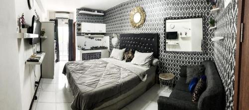 - une chambre avec un lit, un canapé et un miroir dans l'établissement Megaroom Cinere Resort Apartment, à Gandul