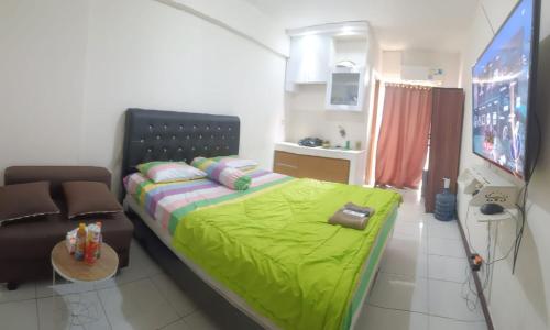 - une chambre avec un lit vert et un canapé dans l'établissement Megaroom Cinere Resort Apartment, à Gandul