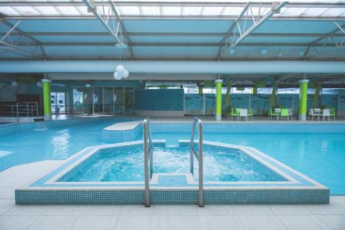 a large swimming pool with blue water in a building at Ormesby 8, Haven Holiday Park, Caister - Four Bedroom, sleeps 8, pets welcome - 2 minutes from the beach! in Great Yarmouth