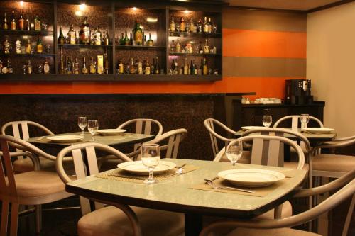 a restaurant with tables and chairs with wine glasses at Riviera Mansion Hotel in Manila
