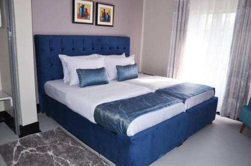 uma cama azul com duas almofadas azuis num quarto em RX Suites em Arua