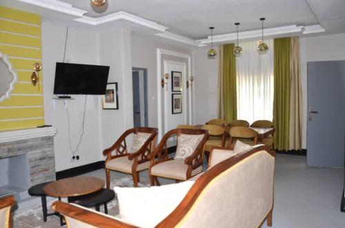 a living room with a table and chairs and a tv at RX Suites in Arua