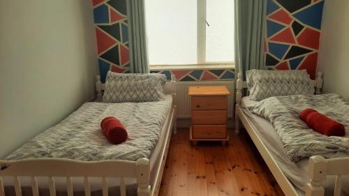 Habitación pequeña con 2 camas con almohadas rojas. en Cobh Rambler, en Cobh