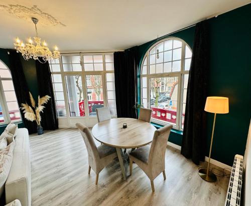 une salle à manger avec une table et des chaises en bois dans l'établissement Appartement de Charme avec Balcon - Villa les IRIS, à Dunkerque