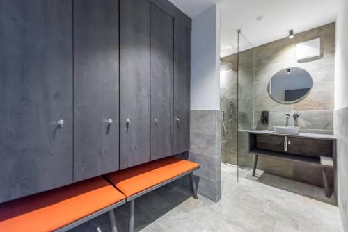 an orange bench in a bathroom with a sink and a mirror at Hotel Wochtla Buam in Brunico