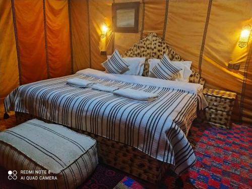 a bedroom with a large bed with two pillows at Luxury Camp Camelhouse in Merzouga