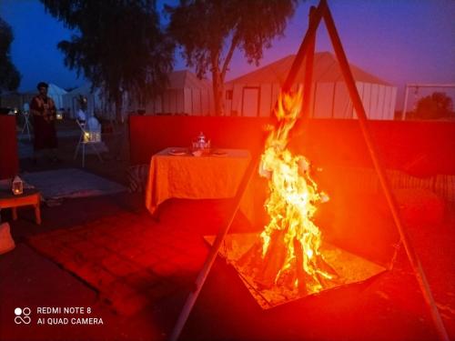 a fire in a tent with a table in the background at Luxury Camp Camelhouse in Merzouga