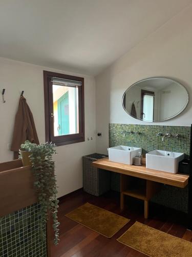 uma casa de banho com 2 lavatórios e um espelho em Nido Appartamento em Cavallino-Treporti