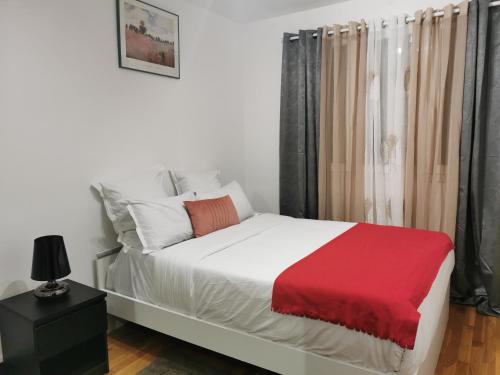 une chambre avec un lit avec une couverture rouge dessus dans l'établissement Appartement meublés à Villeurbanne Lyon, à Villeurbanne
