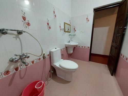a pink and white bathroom with a toilet and sink at Marari Beach Homestay in Mararikulam